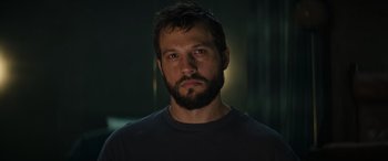 Movie still from “Upgrade” (2018), directed by Leigh Whannell – A man with a goatee and a beard stares at the camera; Close Up shot, Low angle