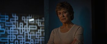 Movie still from “Upgrade” (2018), directed by Leigh Whannell – An older woman standing in front of a blue wall; Close Up shot, Low angle