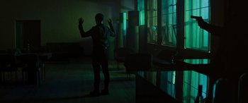 Movie still from “Upgrade” (2018), directed by Leigh Whannell – A man standing in a dark room looking out a window; Wide shot, High angle