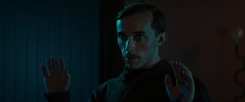 Movie still from “Upgrade” (2018), directed by Leigh Whannell – A man in a black shirt is looking at the camera; Close Up shot, Over the shoulder angle