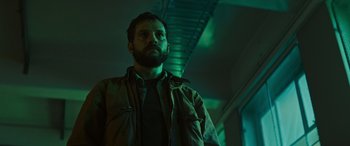 Movie still from “Upgrade” (2018), directed by Leigh Whannell – A man with a beard is standing in a dark room; Close Up shot, Low angle