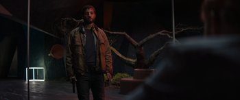 Movie still from “Upgrade” (2018), directed by Leigh Whannell – A man standing in the dark holding a gun; Medium shot, Low angle