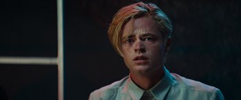 Movie still from “Upgrade” (2018), directed by Leigh Whannell – A young man with blonde hair and blue eyes stares into the camera; Close Up shot, Low angle