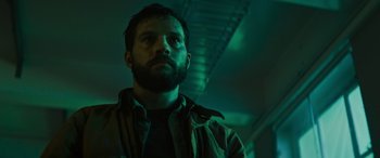 Movie still from “Upgrade” (2018), directed by Leigh Whannell – A man with a goatee standing in a dark room; Close Up shot, Low angle