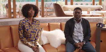 Movie still from “Vacation Friends” (2021), directed by Clay Tarver – A man and a woman sitting on a couch in a room; Medium shot, Over the shoulder angle