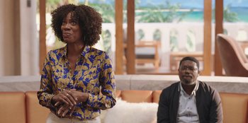 Movie still from “Vacation Friends” (2021), directed by Clay Tarver – A woman standing in front of a man in front of a couch; Medium shot, Over the shoulder angle