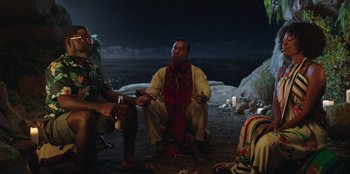 Movie still from “Vacation Friends” (2021), directed by Clay Tarver – A group of people sitting on the ground at night; Medium shot, Over the shoulder angle