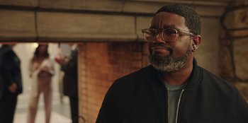 Movie still from “Vacation Friends” (2021), directed by Clay Tarver – A person wearing glasses and a jacket; Close Up shot, Over the shoulder angle