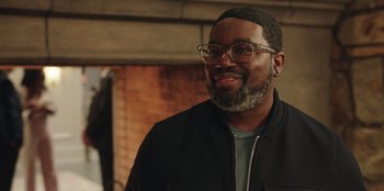 Movie still from “Vacation Friends” (2021), directed by Clay Tarver – A person wearing glasses and a jacket; Close Up shot, Over the shoulder angle