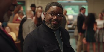 Movie still from “Vacation Friends” (2021), directed by Clay Tarver – A person wearing glasses and a jacket; Close Up shot, Over the shoulder angle