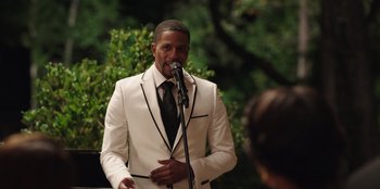 Movie still from “Vacation Friends” (2021), directed by Clay Tarver – A man in a white suit is speaking into a microphone; Medium shot, Over the shoulder angle