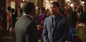 Movie still from “Vacation Friends” (2021), directed by Clay Tarver – A man in a suit talking to another man in a suit; Medium shot, Over the shoulder angle