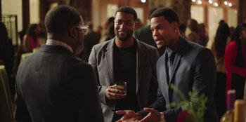 Movie still from “Vacation Friends” (2021), directed by Clay Tarver – A group of men standing next to each other talking; Medium shot, Over the shoulder angle