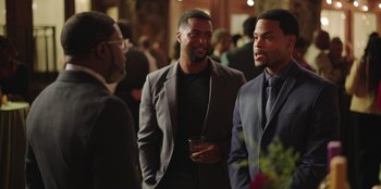 Movie still from “Vacation Friends” (2021), directed by Clay Tarver – A group of men standing next to each other at an event; Medium shot, Over the shoulder angle