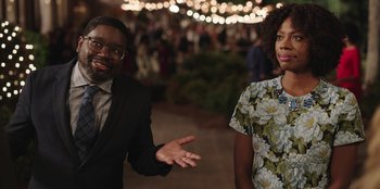 Movie still from “Vacation Friends” (2021), directed by Clay Tarver – A man and a woman standing next to each other in front of lights; Medium shot, Over the shoulder angle
