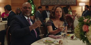 Movie still from “Vacation Friends” (2021), directed by Clay Tarver – A man and a woman sitting at a table with wine glasses; Medium shot, Over the shoulder angle