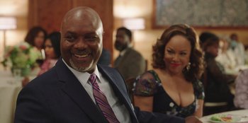 Movie still from “Vacation Friends” (2021), directed by Clay Tarver – A man and a woman smiling for the camera; Medium shot, Over the shoulder angle