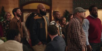 Movie still from “Vacation Friends” (2021), directed by Clay Tarver – A group of men and women standing next to each other in a room; Medium shot, Over the shoulder angle