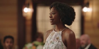 Movie still from “Vacation Friends” (2021), directed by Clay Tarver – A woman in a white dress is looking to her left; Close Up shot, Over the shoulder angle