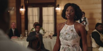 Movie still from “Vacation Friends” (2021), directed by Clay Tarver – A woman standing in front of a man in front of a table; Medium shot, Over the shoulder angle