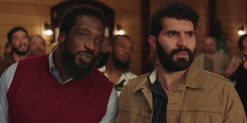 Movie still from “Vacation Friends” (2021), directed by Clay Tarver – A group of men standing next to each other in a room; Close Up shot, Low angle