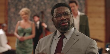 Movie still from “Vacation Friends” (2021), directed by Clay Tarver – A man in a suit and a red neck tie; Close Up shot, Over the shoulder angle