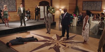Movie still from “Vacation Friends” (2021), directed by Clay Tarver – Two men in suits standing on a wooden floor; Extreme Wide shot, High angle