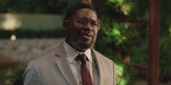 Movie still from “Vacation Friends” (2021), directed by Clay Tarver – A man in a suit and tie wearing glasses; Close Up shot, Over the shoulder angle