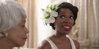 Movie still from “Vacation Friends” (2021), directed by Clay Tarver – A woman wearing a white dress and a flower in her hair; Close Up shot, Over the shoulder angle