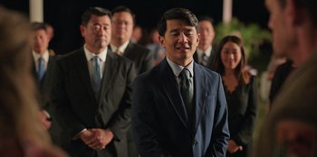 Movie still from “Vacation Friends 2” (2023), directed by Clay Tarver – A group of people in suits and ties standing in a line; Medium shot, Over the shoulder angle