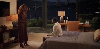 Movie still from “Vacation Friends 2” (2023), directed by Clay Tarver – A man sitting on top of a bed next to a woman; Wide shot, Over the shoulder angle