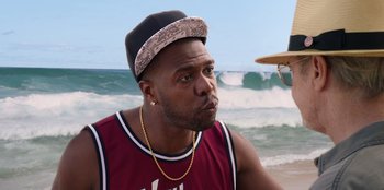 Movie still from “Vacation Friends 2” (2023), directed by Clay Tarver – A person with a hat; Close Up shot, Over the shoulder angle