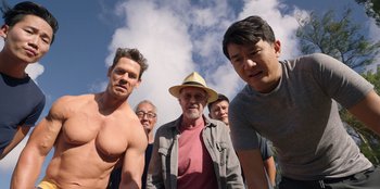 Movie still from “Vacation Friends 2” (2023), directed by Clay Tarver – A group of men standing next to each other in front of a cloudy sky; Medium shot, Low angle