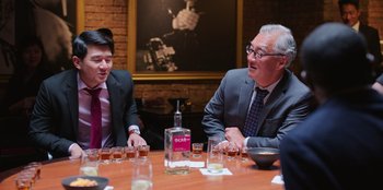 Movie still from “Vacation Friends 2” (2023), directed by Clay Tarver – A group of people sitting at a table with drinks; Medium shot, Over the shoulder angle