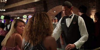 Movie still from “Vacation Friends 2” (2023), directed by Clay Tarver – A man standing at a roulette table in front of a woman; Medium shot, Over the shoulder angle