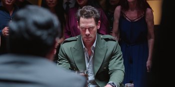 Movie still from “Vacation Friends 2” (2023), directed by Clay Tarver – A person sitting at a table; Medium shot, Over the shoulder angle