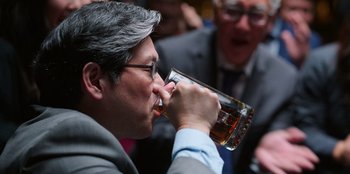 Movie still from “Vacation Friends 2” (2023), directed by Clay Tarver – A person drinking a glass of beer; Close Up shot, Over the shoulder angle