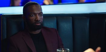 Movie still from “Vacation Friends 2” (2023), directed by Clay Tarver – A man sitting in a booth with a glass of wine; Close Up shot, Over the shoulder angle