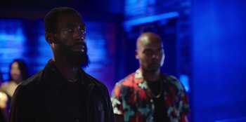 Movie still from “Vacation Friends 2” (2023), directed by Clay Tarver – Two men standing next to each other in front of a blue background; Medium shot, Low angle