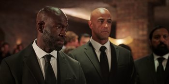 Movie still from “Vacation Friends 2” (2023), directed by Clay Tarver – A couple of men in suits standing next to each other; Close Up shot, Low angle