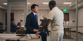 Movie still from “Vacation Friends 2” (2023), directed by Clay Tarver – A man in a business suit and a man in a white t - shirt; Medium shot, Over the shoulder angle