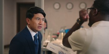 Movie still from “Vacation Friends 2” (2023), directed by Clay Tarver – A man in a suit and tie looking into the distance; Close Up shot, Over the shoulder angle