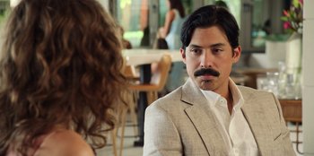 Movie still from “Vacation Friends 2” (2023), directed by Clay Tarver – A man in a suit and a woman in a white shirt; Close Up shot, Over the shoulder angle