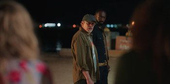 Movie still from “Vacation Friends 2” (2023), directed by Clay Tarver – A man standing next to another man on a street; Medium shot, Over the shoulder angle