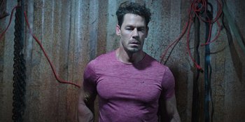 Movie still from “Vacation Friends 2” (2023), directed by Clay Tarver – A man in a red shirt is standing in front of a brick wall; Medium shot, High angle