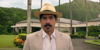 Movie still from “Vacation Friends 2” (2023), directed by Clay Tarver – A man in a tan suit and a straw hat; Close Up shot, Over the shoulder angle