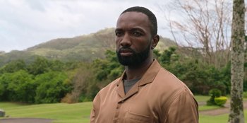 Movie still from “Vacation Friends 2” (2023), directed by Clay Tarver – A man with a beard is standing in front of a field; Close Up shot, Over the shoulder angle