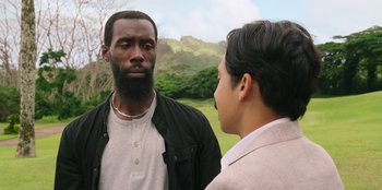 Movie still from “Vacation Friends 2” (2023), directed by Clay Tarver – Two men standing next to each other on a field; Close Up shot, Over the shoulder angle