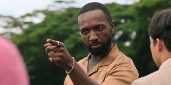 Movie still from “Vacation Friends 2” (2023), directed by Clay Tarver – A man holding a cigarette in his hand; Close Up shot, Over the shoulder angle