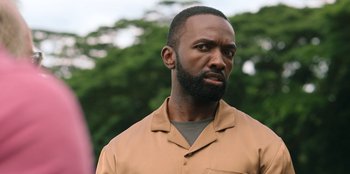 Movie still from “Vacation Friends 2” (2023), directed by Clay Tarver – A man with a black beard is standing in front of a tree; Close Up shot, Over the shoulder angle